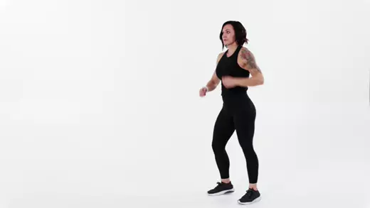 زن ورزشکار پرانرژی در حال مشت زدن در هوا برای چربیسوزی و فرمدهی بازوها در تمرین خانگی